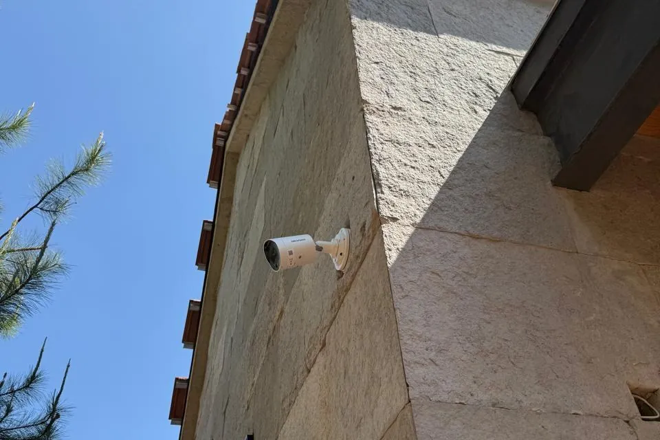 Cámara de seguridad instalada en la fachada de piedra de una casa