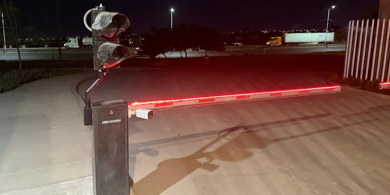 Barrera vehicular con sus luces encendidas en un acceso, de noche